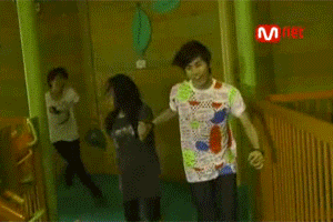 a man in a colorful shirt is dancing in a room with a mnet logo in the background