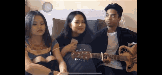 a group of young people are sitting on a couch playing guitars