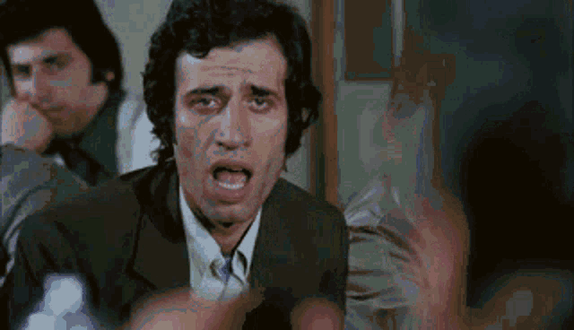 a man in a suit and tie is making a funny face with his mouth open