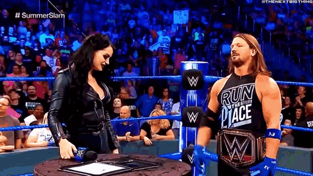 a man and a woman are standing in a wrestling ring . the man is wearing a shirt that says run place .