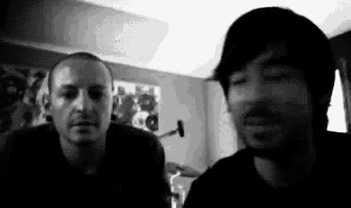 two men are sitting next to each other in a room and talking to each other .