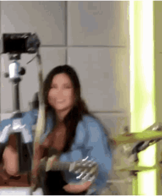 a woman is playing a guitar in a room with a camera in the background .