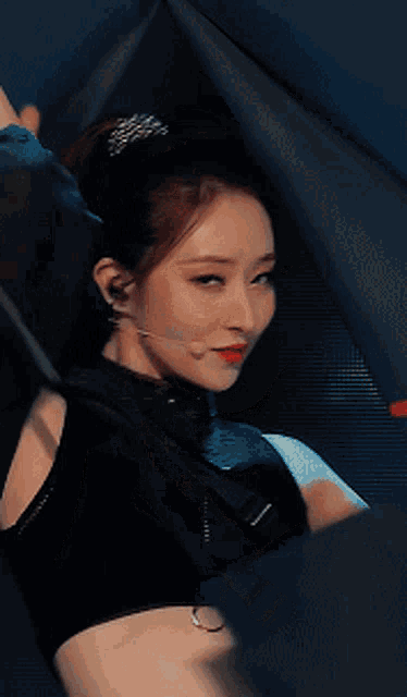 a woman wearing a black crop top with the letter o on the waistband