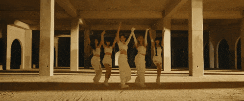 a group of women in white dresses are dancing in an empty room