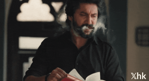 a man with a beard is smoking a cigar with xhk written on the bottom