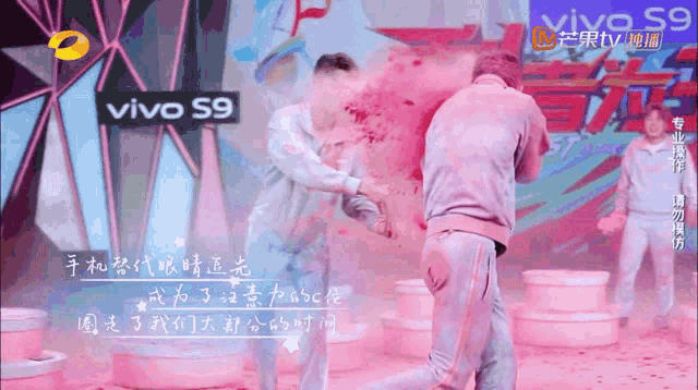 a man is being sprayed with pink paint by another man in front of a vivo s9 ad