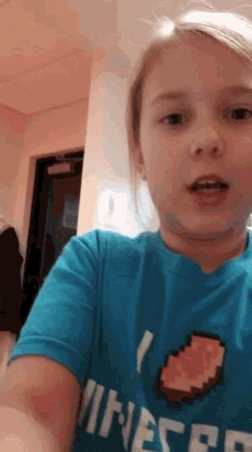 a young girl wearing a blue shirt that says " i love minecraft "