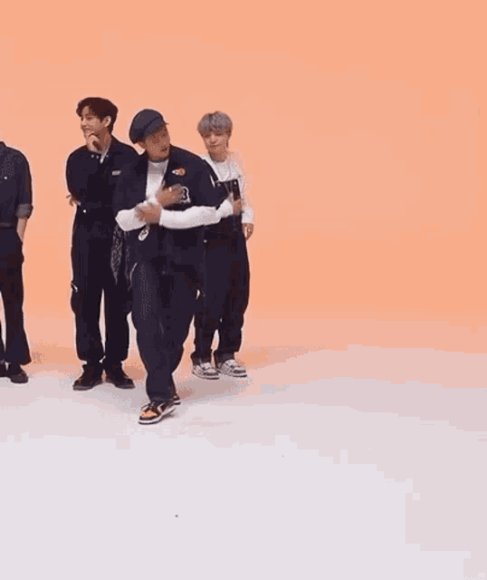 a group of young men are dancing together on a white surface .