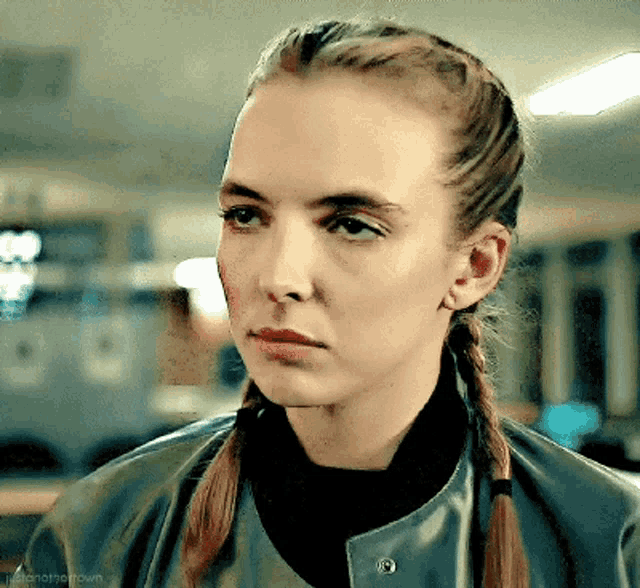 a close up of a woman 's face with braids and a leather jacket .