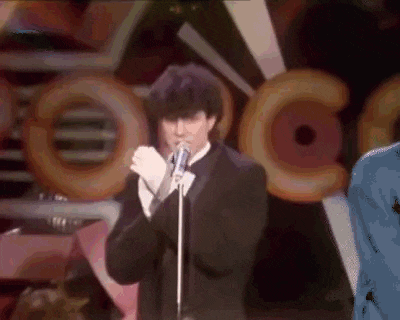 a man in a tuxedo is singing into a microphone on a stage .