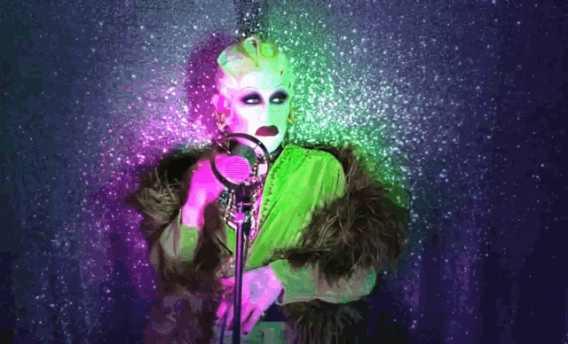 a drag queen singing into a microphone with a purple background