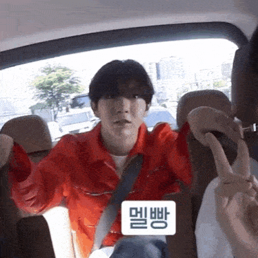 a man in a red jacket is sitting in the back seat of a car with another man