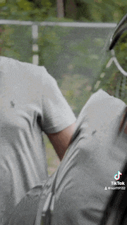 a man in a grey shirt is holding a tennis racquet in his hand .
