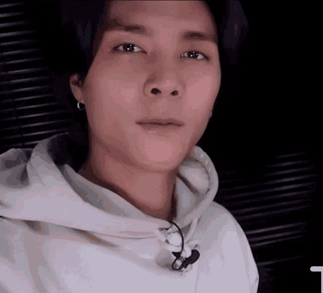 a close up of a person wearing a white hoodie with the letter t in the corner