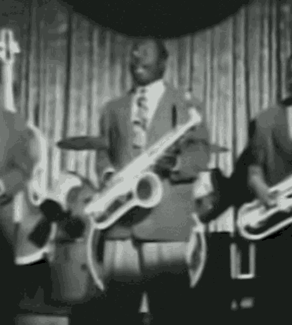 a black and white photo of a band playing instruments on stage