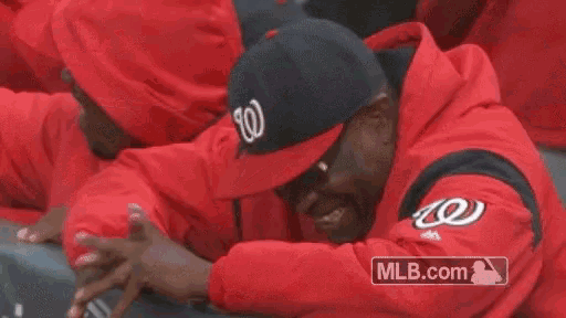 a man wearing a washington nationals hat is sitting in a dugout