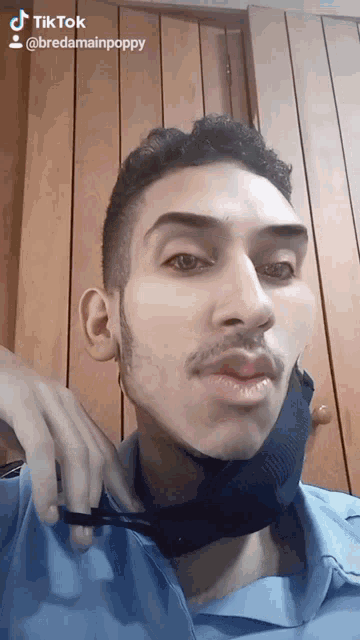 a man wearing a blue shirt and a black face mask has a tiktok sticker on his face