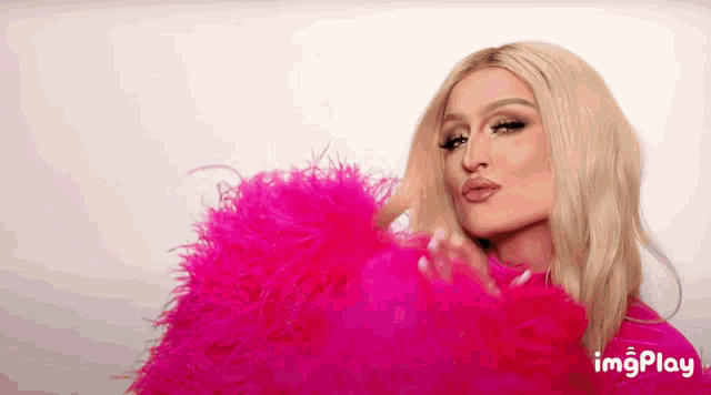 a woman is wearing a pink feathered jacket and making a face .