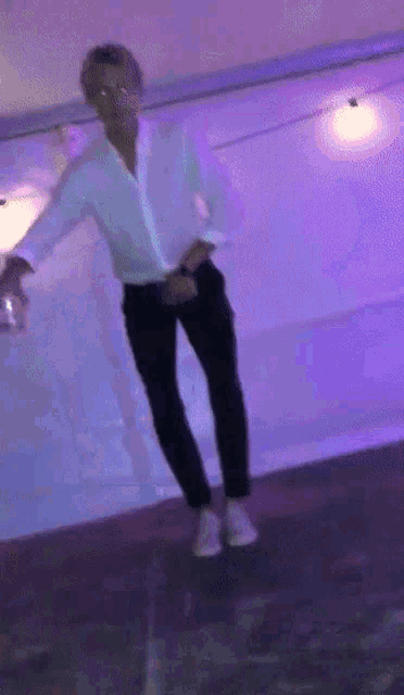 a man in a white shirt and black pants is dancing on a purple background