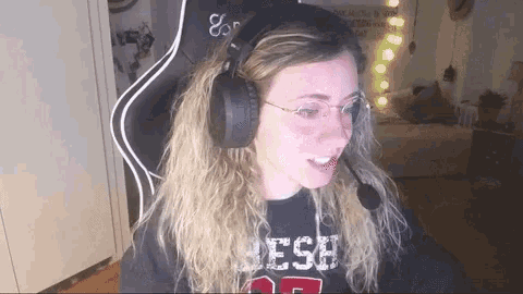a woman wearing headphones and glasses is sitting in front of a computer screen .