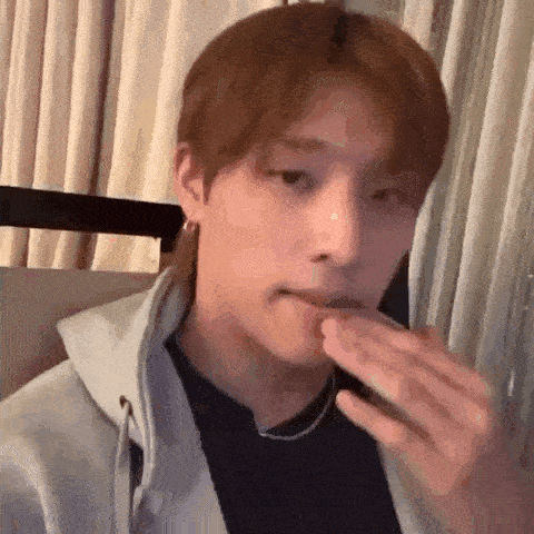 a young man is sitting in a chair eating something with his hand .