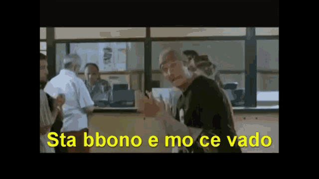 a man standing in front of a window with the words sta bbono e mo ce vado written in yellow