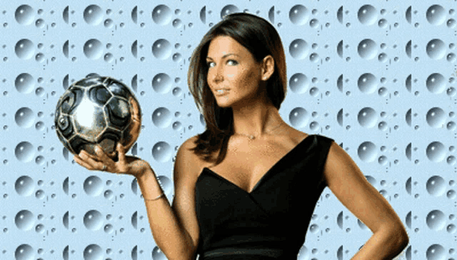 a woman in a black dress is holding a silver soccer ball