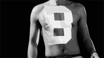 a man without a shirt is wearing a number eight on his chest .
