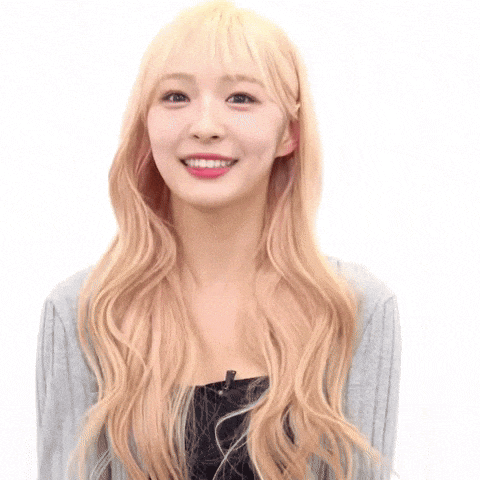 a young woman with long blonde hair is smiling and wearing a gray sweater .