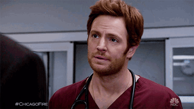 a man with a stethoscope around his neck is wearing a red scrub top that says nbc