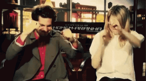 a man and a woman covering their faces in front of a sign that says homem-aranha