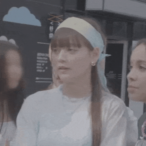 a woman wearing a headband and earrings is standing next to another woman .