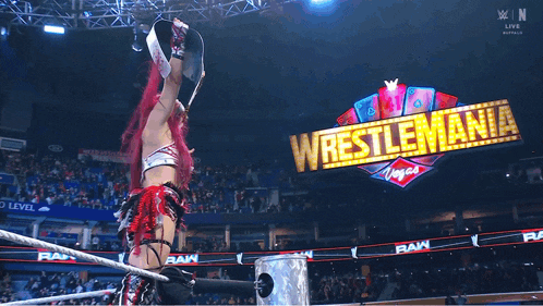 a woman in a wrestling ring with a sign that says wrestlemania