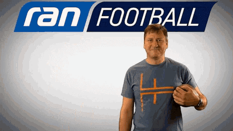 a man holds a football in front of a sign that says ran football