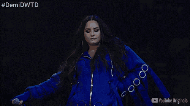 a woman in a blue jacket is dancing on a stage in front of a youtube originals logo