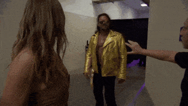 a man in a gold jacket and sunglasses talks to a woman