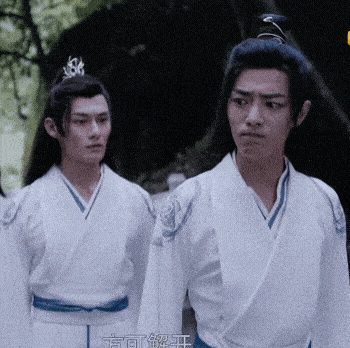 two men in white kimonos are standing next to each other and one has a crown on his head