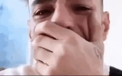 a man is covering his mouth with his hands .