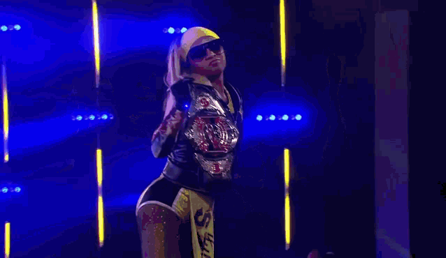 a female wrestler is holding a championship belt in her hand