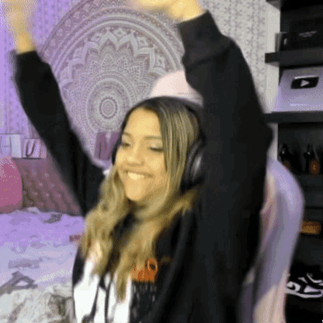a woman wearing headphones is raising her arms in the air while sitting in a chair .