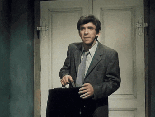 a man in a suit and tie holds a briefcase