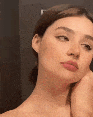 a close up of a woman 's face with her hand on her face .