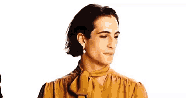 a man wearing a yellow shirt and pearl earrings is making a face .
