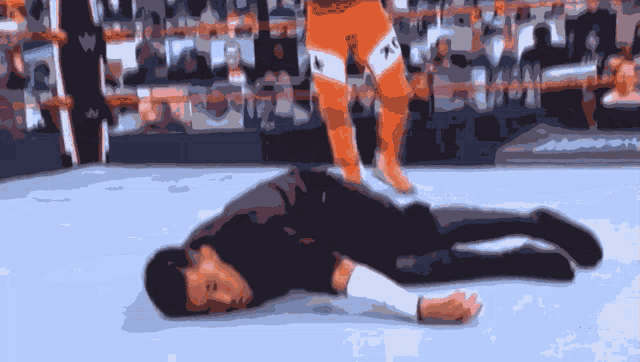 a man laying on the ground with a wrestler standing behind him with a tag that says tna on his leg