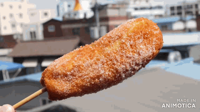 a person is holding a fried food on a stick with the words made in animotica on the bottom
