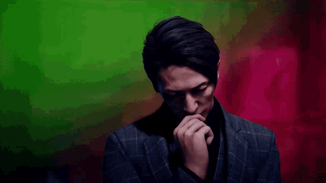 a man in a suit has his hand on his chin in front of a red and green background