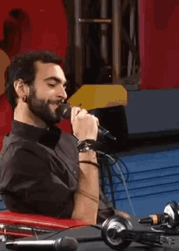 a man singing into a microphone with headphones on the table