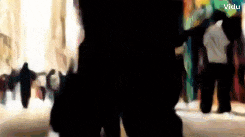 a blurry picture of people walking down a street with the words vidu in the corner