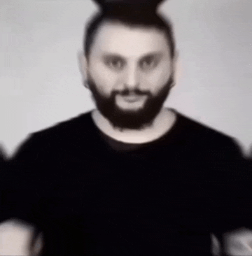 a man with a beard is wearing a black t-shirt and a black hat .