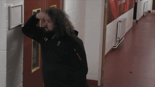 a man leaning against a wall in a hallway with bbc written on the corner